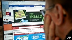 FILE - A journalist looks at webpages showing Cyber Monday deals by online retailers, Nov. 26, 2018, in New York. The physical rush of Black Friday and the armchair browsing of Cyber Monday are increasingly blending into one big holiday shopping event.