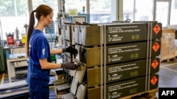 FILE - An employee of German armaments company Rheinmetall packs boxes of ammunition for Leopard battle tanks that will be delivered to Ukrainian forces, at its facility in Unterluess, Germany, June 6, 2023. 