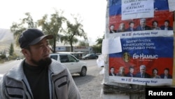 A local resident looks at election campaign posters, which are on display in the village of Vorontsovka near the capital Bishkek, Kyrgyzstan, Oct. 1, 2015.