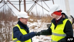 Міністр енергетики Латвії Каспарс Мельніс (п) і Роландс Іркліс, генеральний директор державного оператора системи передачі електроенергії AST, святкують відключення основної лінії електропередач між Латвією та Росією. Вілака, Латвія, біля російського кордону, 8 лютого 2025 року.