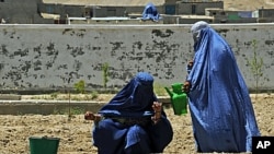 Two Afghan women water the soil at the Qalat Department of Women's Affairs, in the Zabul Province of Afghanistan, May 8, 2011