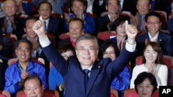 South Korea's presidential candidate Moon Jae-in of the Democratic Party raises his hands as his party leaders and members watch on television local media's results of exit polls for the presidential election in Seoul, South Korea, May 9, 2017. 