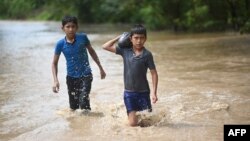 ARCHIVO: Dos niños vadean un área inundada en Pazos, Guatemala, después del paso del huracán Eta el 6 de noviembre de 2020.