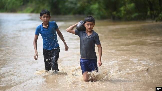 ARCHIVO: Dos niños vadean un área inundada en Pazos, Guatemala, después del paso del huracán Eta el 6 de noviembre de 2020.
