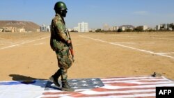 FILE - A fighter with Iran-backed Houthis walks on the flags of Israel and the US during a rally the Iran-backed group held in Sanaa in solidarity with the Palestinian Hamas movement's armed resistance against Israel on January 29, 2024.