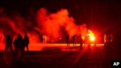 Youths stand in a field during clashes as police tried to break up an unauthorized rave near Redon, Brittany, June 18, 2021. Police fired tear gas and charged clusters of violent partiers, who hurled metal balls and other projectiles in return.