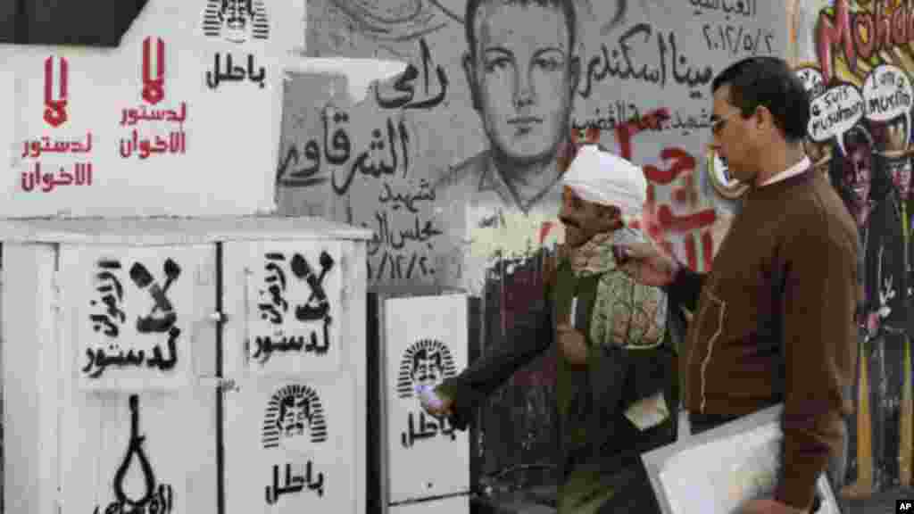 Egyptian walk next to graffiti and Arabic writing that reads at left, "no to the Muslim Brotherhood constitution," in Tahrir Square in Cairo, Egypt,, Monday, Dec. 10, 2012. (AP Photo/Hassan Ammar)