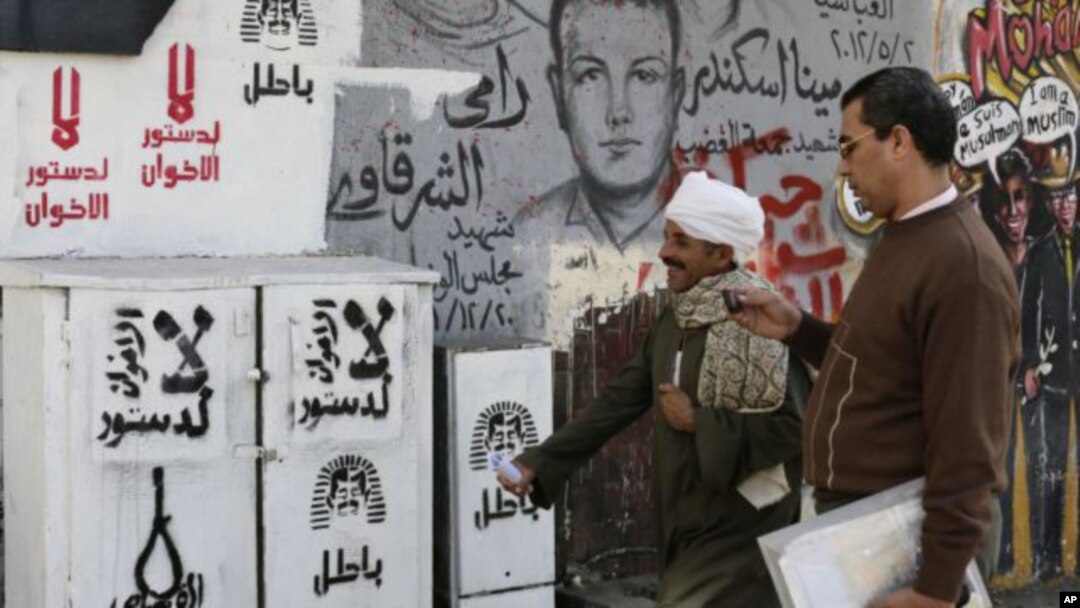 Egipcios pasan junto a un grafiti en la plaza Tahrir en El Cairo en el que se lee: “no a la Constitución de la Hermandad Musulmana”.
