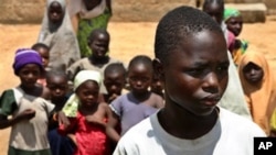 FILE - Anas Mustapha, 14 years old, at right, who was tested with the meningitis epidemic experimental drug, looks on as he stands with some children in Kano, Nigeria, September 7, 2012.