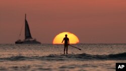 A paddle boarder looks our over the Pacific Ocean as the sun sets off of Waikiki Beach, in Honolulu, on New Years Eve, Dec. 31, 2013. 