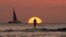 FILE - A paddle boarder looks our over the Pacific Ocean as the sun sets off of Waikiki Beach, in Honolulu.