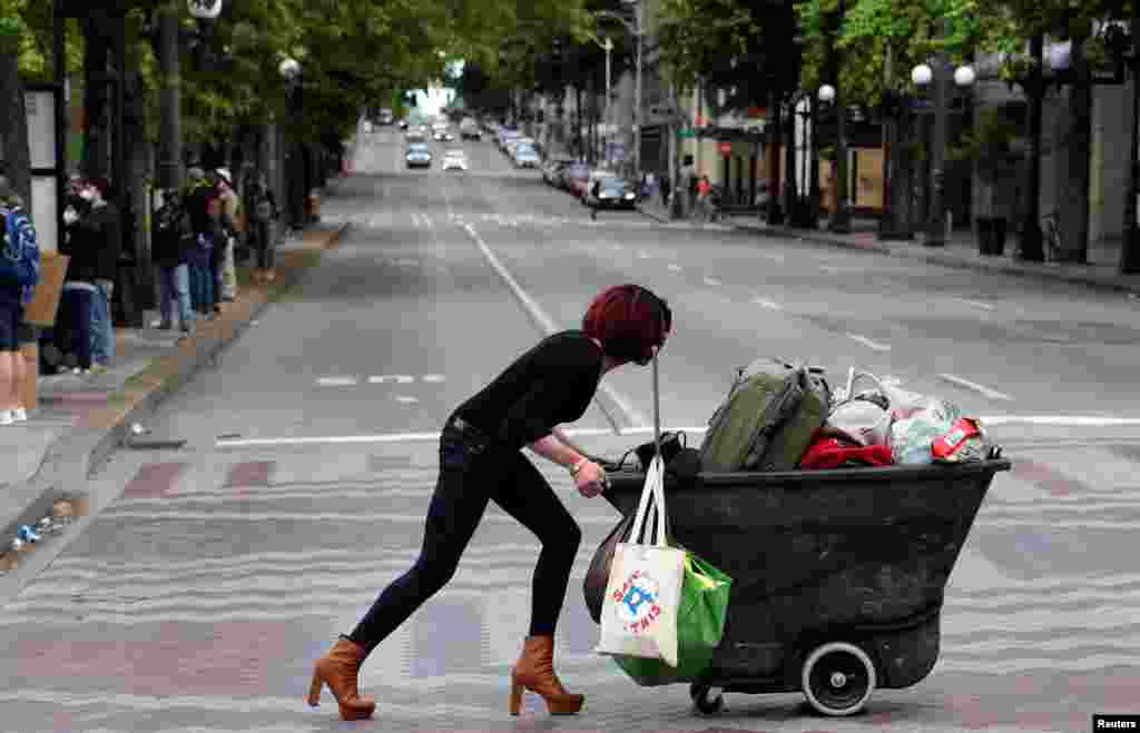 A woman pushes a cart during a protest against racial inequality and call for defunding of Seattle police, in Seattle downtown, Washington, June 14, 2020.