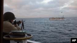 FILE - In this Feb. 22, 2018 photo released by Argentina's Coast Guard, a soldier fires at the Chinese fishing boat named Jing Yuan 626 in Argentine waters. 