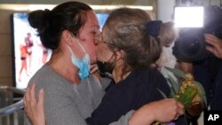 A woman is embraced by a loved one after arriving on a flight from Los Angeles at Sydney Airport as Australia open its borders for the first time in 19 months in Sydney, Nov. 1, 2021.