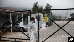 A man wearing a protective suit to protect against coronavirus leaves a migrant facility at Malakasa village, north of Athens, April 5, 2020.