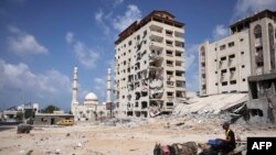 A Palestinian man rides his donkey cart past a building that was destroyed during the 11-day war in May of this year between Israel and the Palestinian Hamas movement, in Gaza City.