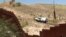 The view from the Mexican side as a U.S. Border Patrol car passes a fence. (G. Flakus/VOA)