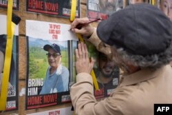 FILE - An Israeli man writes "rescued" on a poster bearing the image of rescued Israeli-Argentinian hostage Louis Har on a wall outside the Ministry of Defence In the coastal city of Tel Aviv on February 12, 2024.