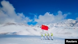 FILE - Auxiliary police and police officers in protective suits patrol the snow-covered border region in Ili Kazakh Autonomous Prefecture, Xinjiang Uyghur Autonomous Region, China, October 7, 2021. (China Daily via REUTERS)