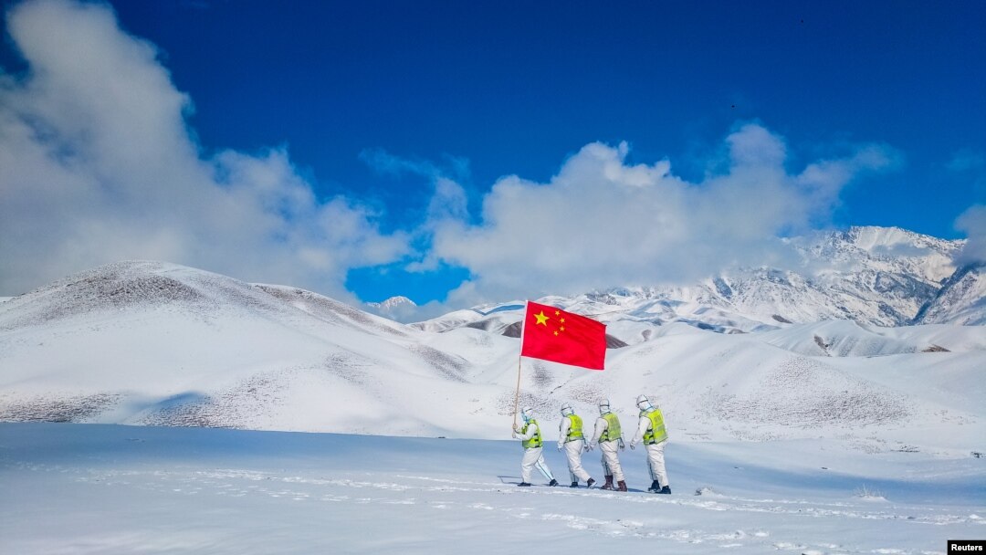 Auxiliary police and police officers in protective suits patrol the snow-covered border region in Ili Kazakh Autonomous Prefecture, Xinjiang Uyghur Autonomous Region, China, October 7, 2021.