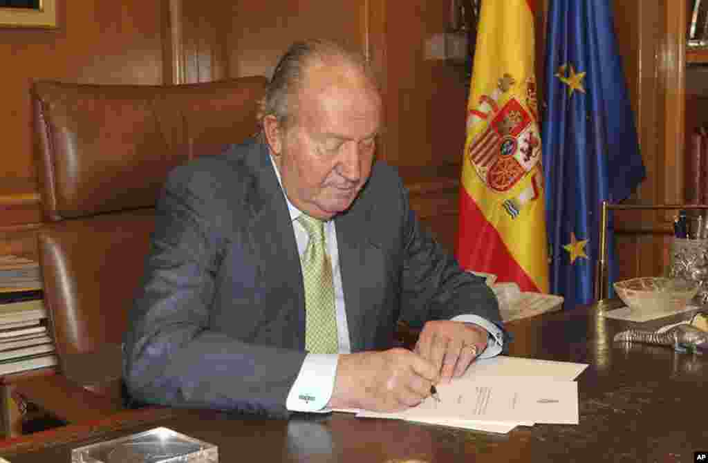 In this photo released by the Royal Palace, Spain's King Juan Carlos signs a document in the Zarzuela Palace opening the way for his abdication, June 2, 2014.