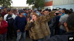 Mirna Contreras, de Honduras, canta mientras otros migrantes esperan en la cola para cenar en un albergue donde viven los miembros de la caravana de migrantes, en Tijuana, México, el lunes 26 de noviembre de 2018.