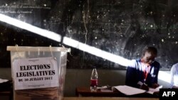 FILE - An election helper sits next to an urn filled with ballots at a polling station in Dakar, July 30, 2017, during parliamentary elections.