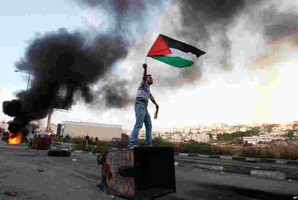 Palestinac ma&scaron;e nacionalnom zastavom protestirajući protiv izraelskih operacija na pojasu Gaze, pokraj Ofera, izraelskog vojnog zatvora pokraj Ramale, 18. novembra 2012.