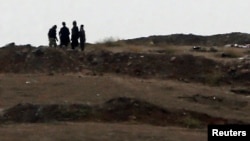 Armed men, presumed to be Islamic State fighters, stand at a checkpoint in the west of Syrian town of Kobani, seen from near the Mursitpinar border crossing on the Turkish-Syrian border, Oct. 13, 2014.