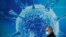 Great Britain, A man wearing a protective face mask walks past an illustration of a virus outside a regional science centre