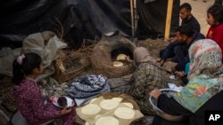 FILE - Palestinians displaced by the Israeli bombardment of the Gaza Strip cook at the makeshift tent camp in the Muwasi area on December 28, 2023.