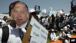 A protester wears a mask depicting Israel's Prime Minister Benjamin Netanyahu during a rally in front of the Knesset, the Israeli parliament, in Jerusalem July 31, 2011
