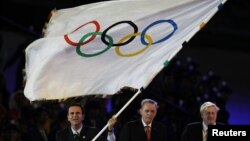 Walikota Rio de Janeiro Eduardo Paes (kiri) melambaikan bendera Olimpiade di London, 2012.