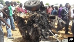 People gather around a car used by a suicide bomber following an explosion in church compound in Bauchi, Nigeria, June 3, 2012.