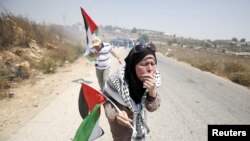 Palestinian protesters holding Palestinian flags react to tear gas fired by Israeli troops during clashes at a protest against Jewish settlements in the West Bank village of Nabi Saleh, near Ramallah August 7, 2015. 