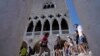 FILE - Tourists walk on a bridge in front of Palazzo Ducale, in Venice, Italy, June 17, 2021. 