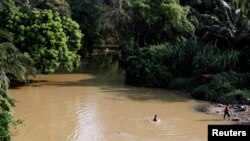 FILE - A boy swims in a river polluted by gold mining waste in Nsuaem district, western Ghana, Nov. 23, 2018. 