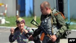 Seorang separatis pro-Rusia membantu seorang perempuan menghindari serangan pasukan Ukraina di Donetsk, Ukraina timur (21/7).