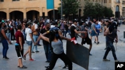 People throw stones during a protest following last week's explosion that killed many and devastated the city, in Beirut, Lebanon, Aug. 11, 2020.