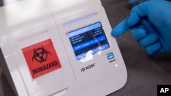 FILE - A scientist runs a mock COVID-19 sample test in Washington, D.C., April 28, 2020. 