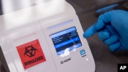 FILE - A scientist runs a mock COVID-19 sample test in Washington, D.C., April 28, 2020. 