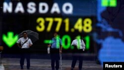 Businessmen are reflected on a board showing the U.S. NASDAQ average outside a brokerage in Tokyo, Oct. 1, 2013. 