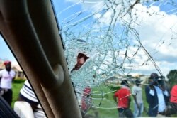 A man peers through the shattered windscreen of the car of Ugandan pop star and presidential candidate Robert Kyagulanyi, also known as Bobi Wine, in Jinja, near Kampala, Uganda, Dec. 1, 2020.