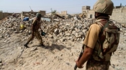 FILE - Pakistani soldiers stand near the debris of a house that was destroyed during a military operation against Taliban militants in the town of Miranshah in North Waziristan, July 9, 2014.