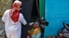 An Indian health worker checks body temperature of a woman during a door-to-door survey being conducted as a precaution against COVID-19 in Hyderabad, India, May 6, 2021.