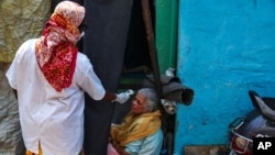 An Indian health worker checks body temperature of a woman during a door-to-door survey being conducted as a precaution against COVID-19 in Hyderabad, India, May 6, 2021.