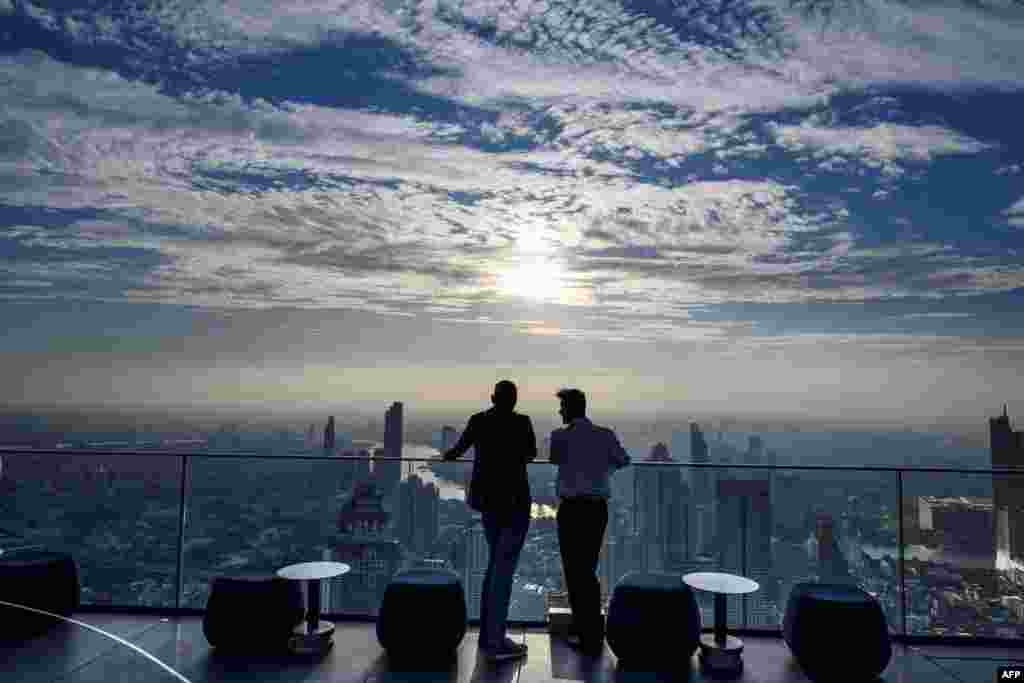 Men enjoy the city skyline view on the 314-meter high rooftop terrace of the Mahanakhon building in Bangkok, Thailand.