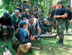 Juru bicara Abu Sayyaf Abu Sabaya, di latar depan, terlihat bersama kelompok ekstremis bersenjata. Pasukan Filipina menangkap seorang komandan pemberontak Abu Sayyaf yang disalahkan atas penculikan uang tebusan selama bertahun-tahun dan pada hari Minggu, 21 Maret 2021. (Foto: AP)