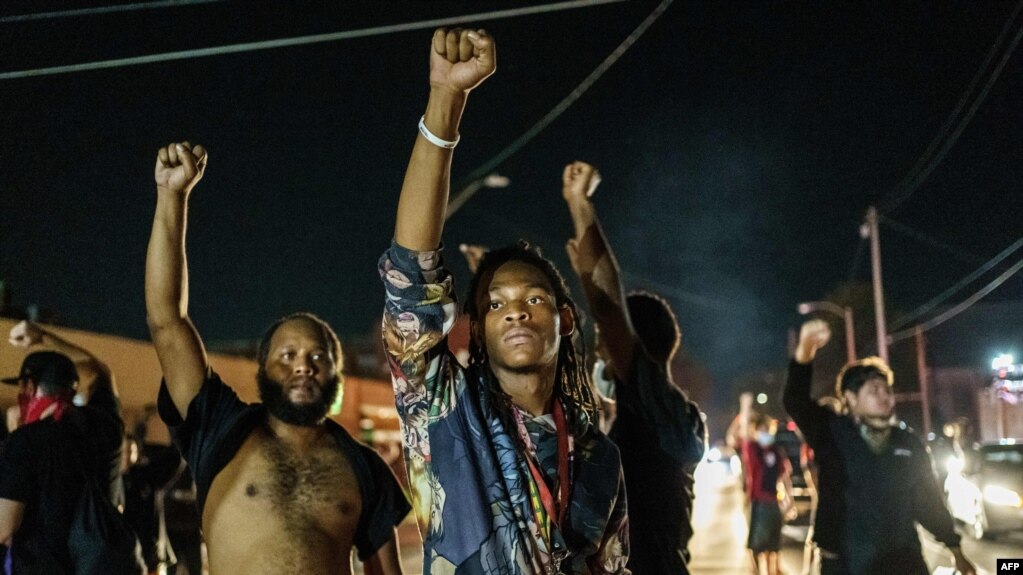 Protesters raise their fists during a demonstration against the shooting of Jacob Blake in Kenosha, Wisconsin on August 26, 2020. - Two people were shot dead and a third injured on the night of August 25 in the US city of Kenosha, Wisconsin.