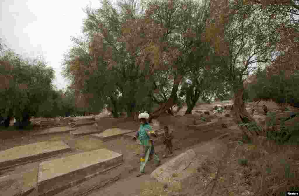 ایک خاتون اپنے بچے کے ساتھ قبرستان سے گزر رہی ہے۔